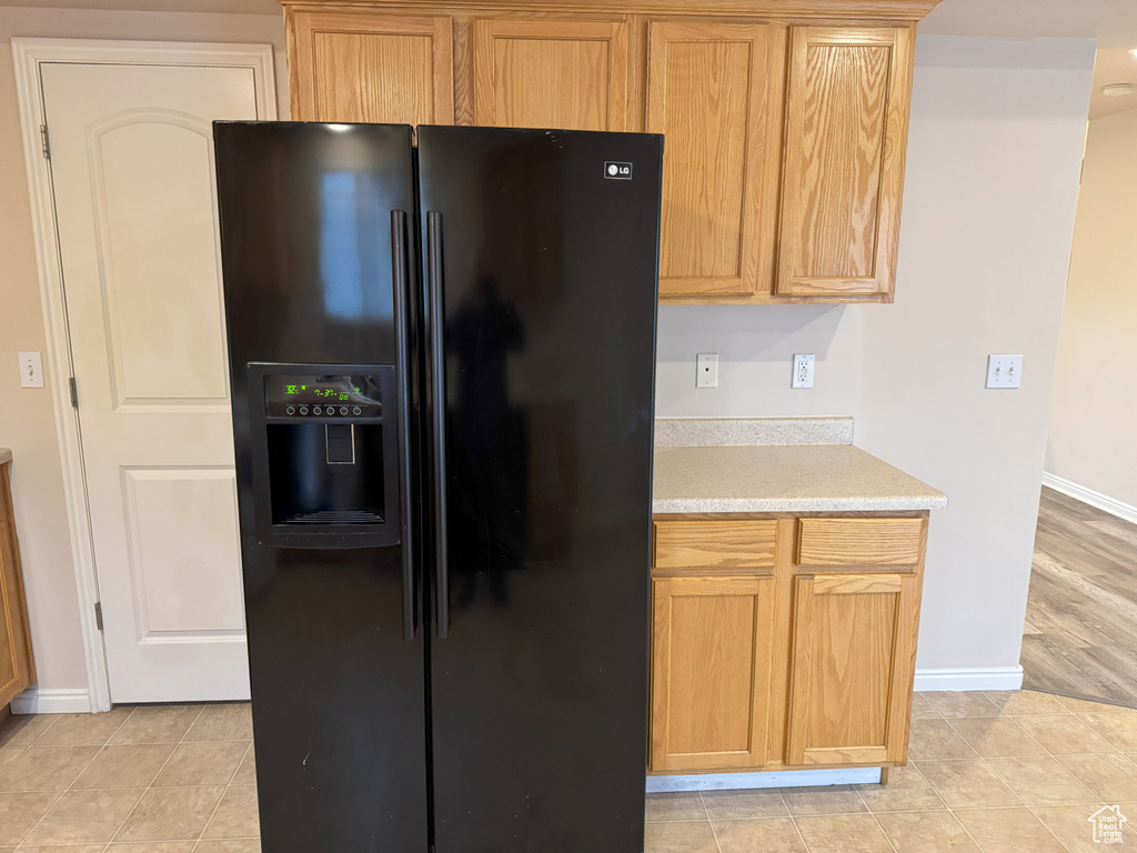 Kitchen featuring black fridge with ice dispenser and light tile patterned floors