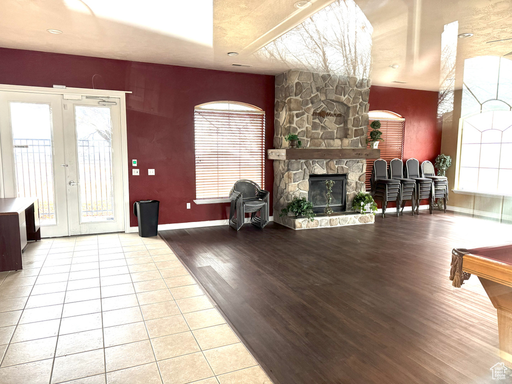 Living room with french doors, light hardwood / wood-style floors, and a stone fireplace