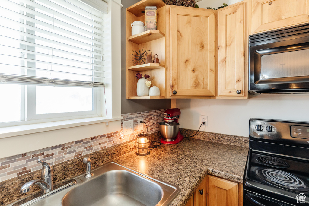 Kitchen featuring black microwave, a sink, light brown cabinets, and range with electric cooktop