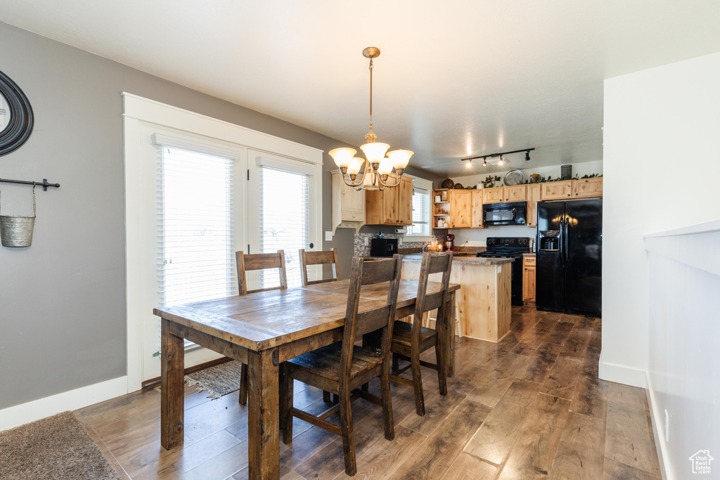 Dining area with track lighting, baseboards, a chandelier, and dark wood finished floors