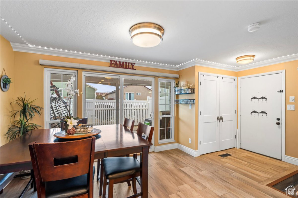 Dining room with crown molding and light hardwood / wood-style flooring