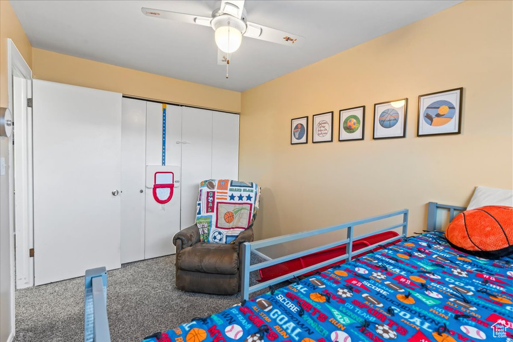 Carpeted bedroom featuring ceiling fan and a closet