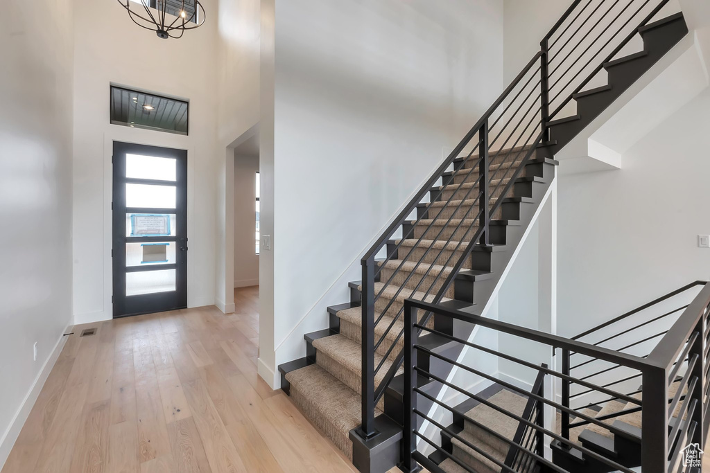 Entrance foyer featuring a high ceiling, light wood-type flooring, and a notable chandelier