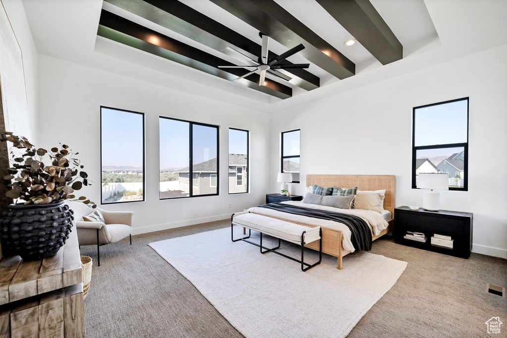 Carpeted bedroom with ceiling fan, beam ceiling, and a towering ceiling