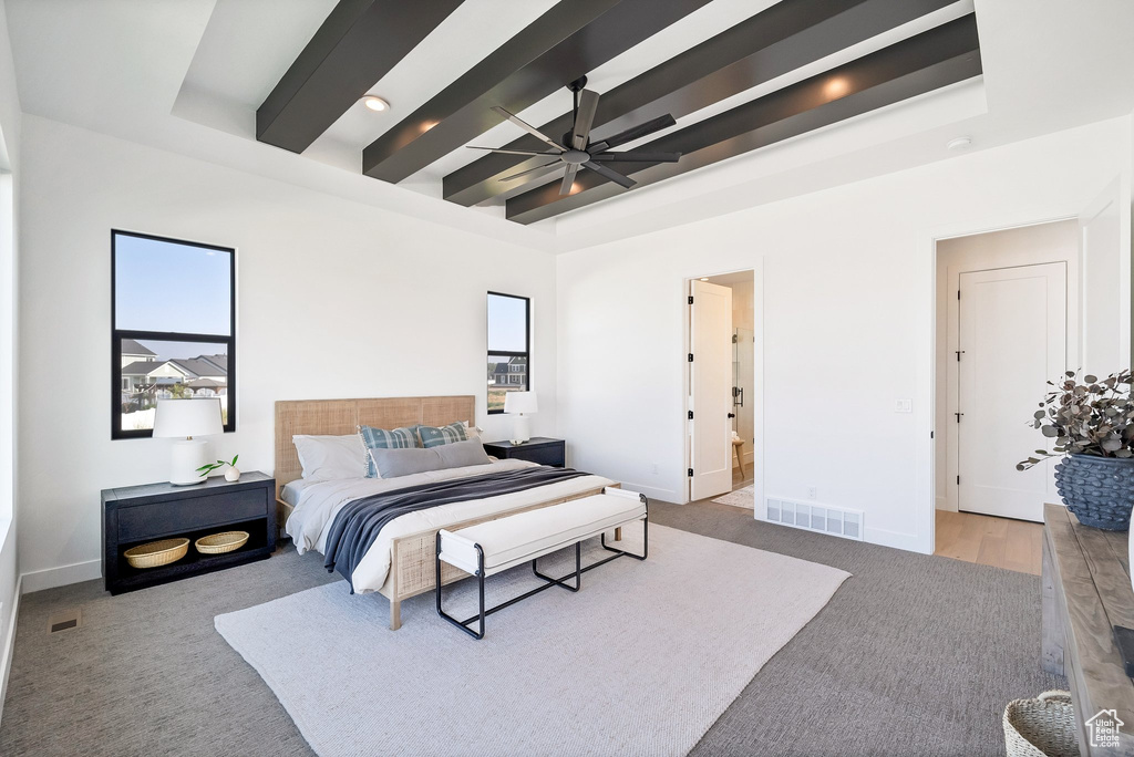 Bedroom featuring beamed ceiling, multiple windows, ensuite bath, and ceiling fan