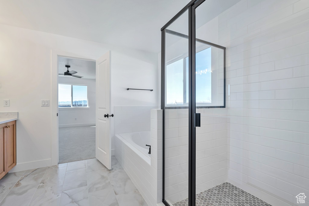 Bathroom featuring ceiling fan, plus walk in shower, and vanity