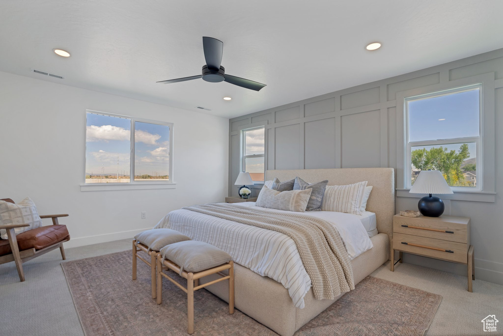 Bedroom with multiple windows, ceiling fan, and light carpet
