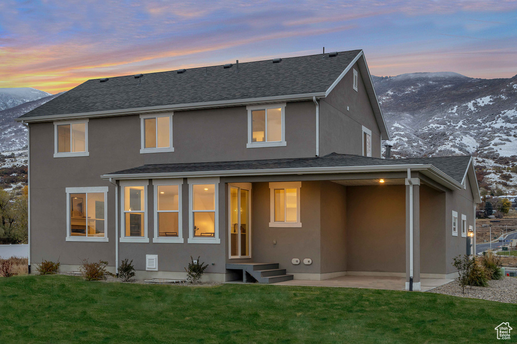 Snow covered property featuring a lawn and a mountain view