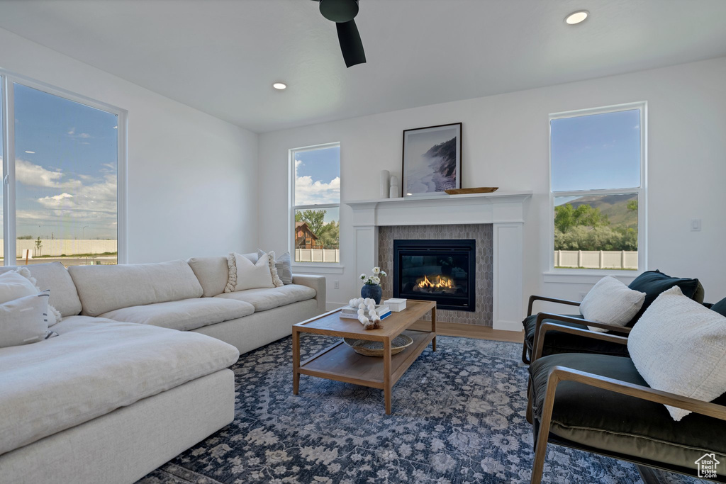 Living room with hardwood / wood-style floors, ceiling fan, a healthy amount of sunlight, and a tiled fireplace