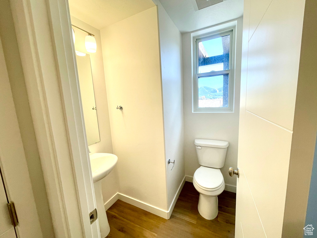 Half bath featuring wood finished floors and toilet