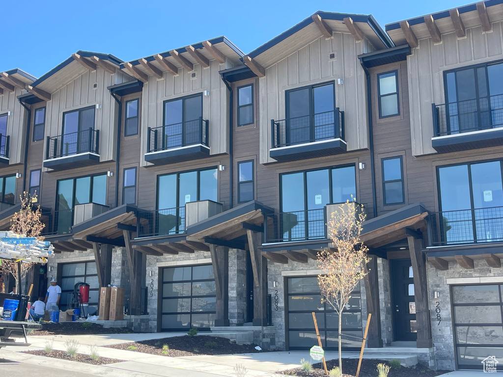View of front of home featuring a garage, stone siding, and board and batten siding