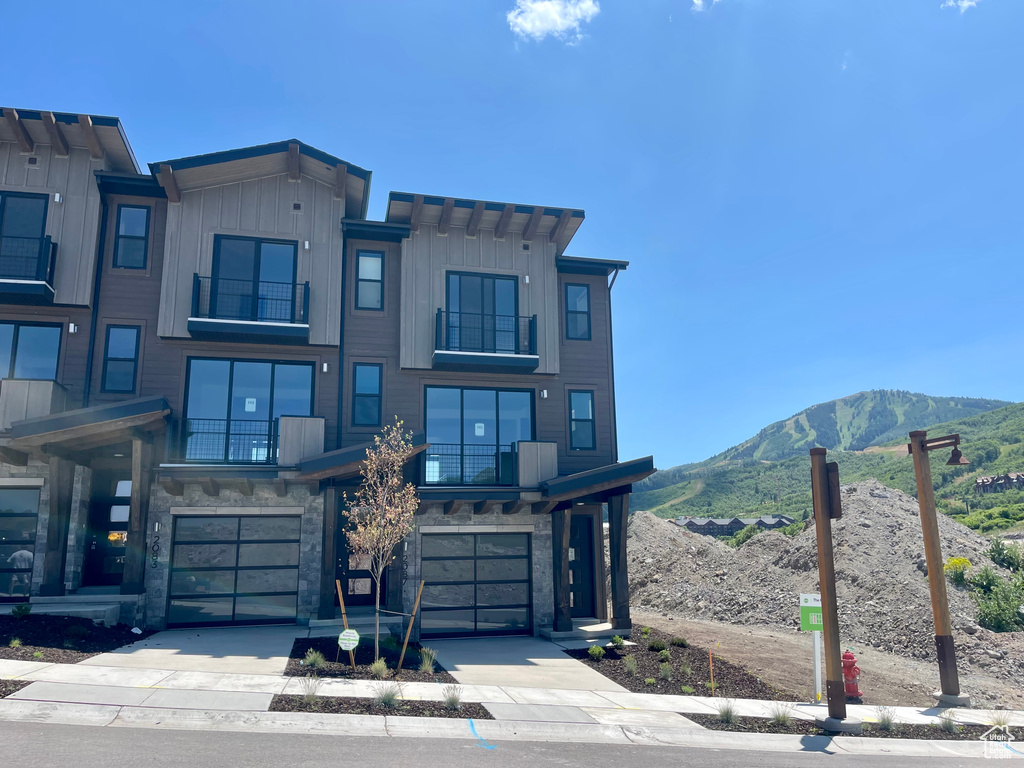 View of front of house featuring a balcony, an attached garage, a mountain view, driveway, and board and batten siding