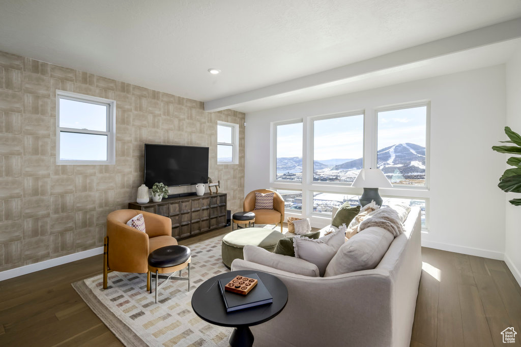 Living room with baseboards, a wealth of natural light, an accent wall, and wood finished floors