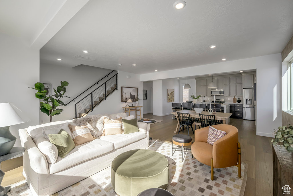 Living area with recessed lighting, plenty of natural light, stairs, and wood finished floors