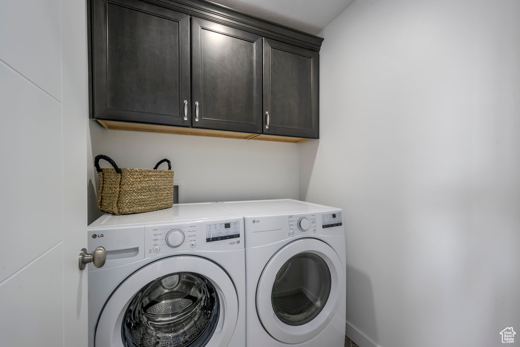 Clothes washing area featuring cabinet space and washing machine and clothes dryer