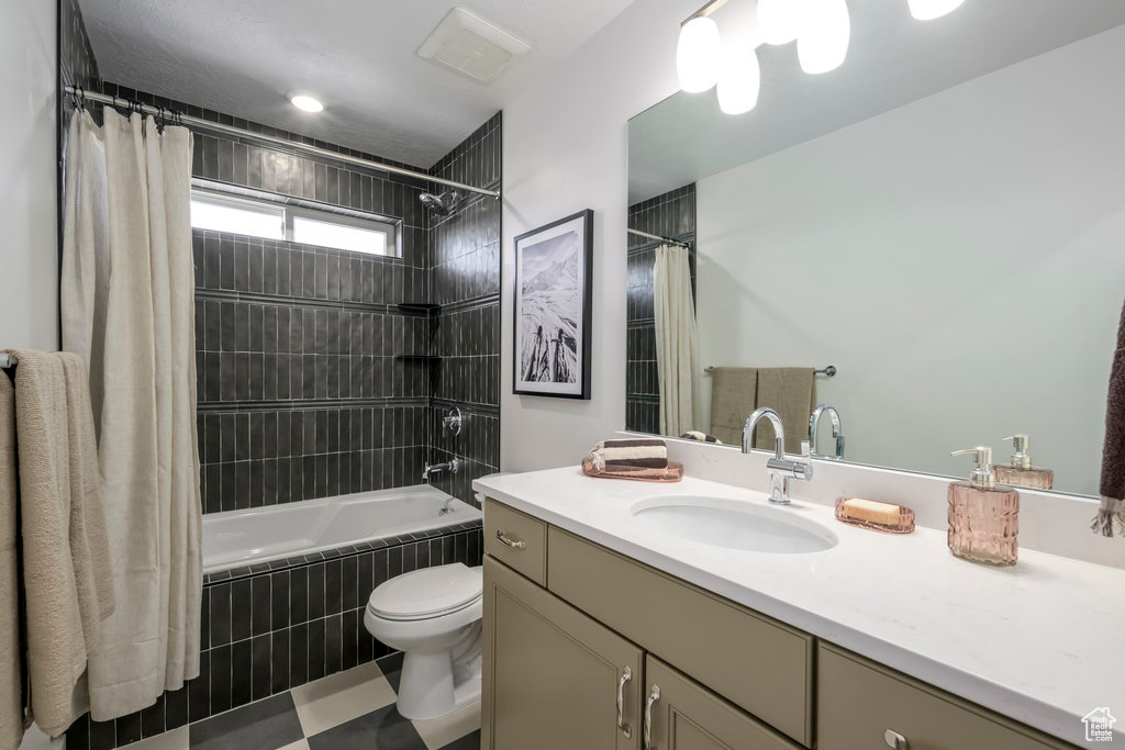 Full bath with vanity, tiled shower / bath, and toilet