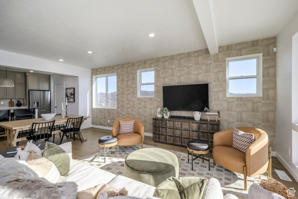 Living area featuring baseboards, a healthy amount of sunlight, an accent wall, and light wood-style floors