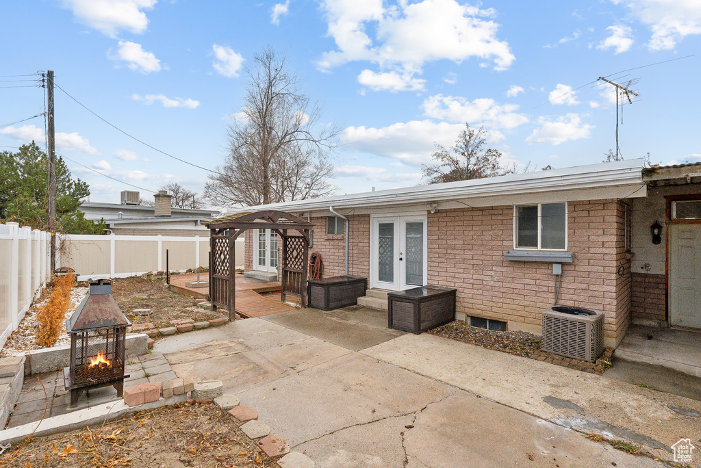 Back of house with a fire pit, central AC, a patio, and french doors