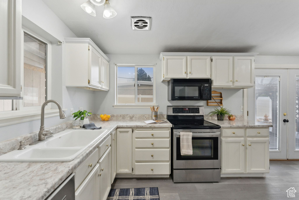 Kitchen with electric range, white cabinetry, and sink