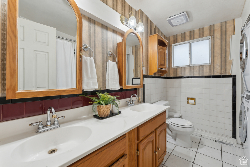 Bathroom with tile patterned flooring, vanity, toilet, and stacked washer / dryer