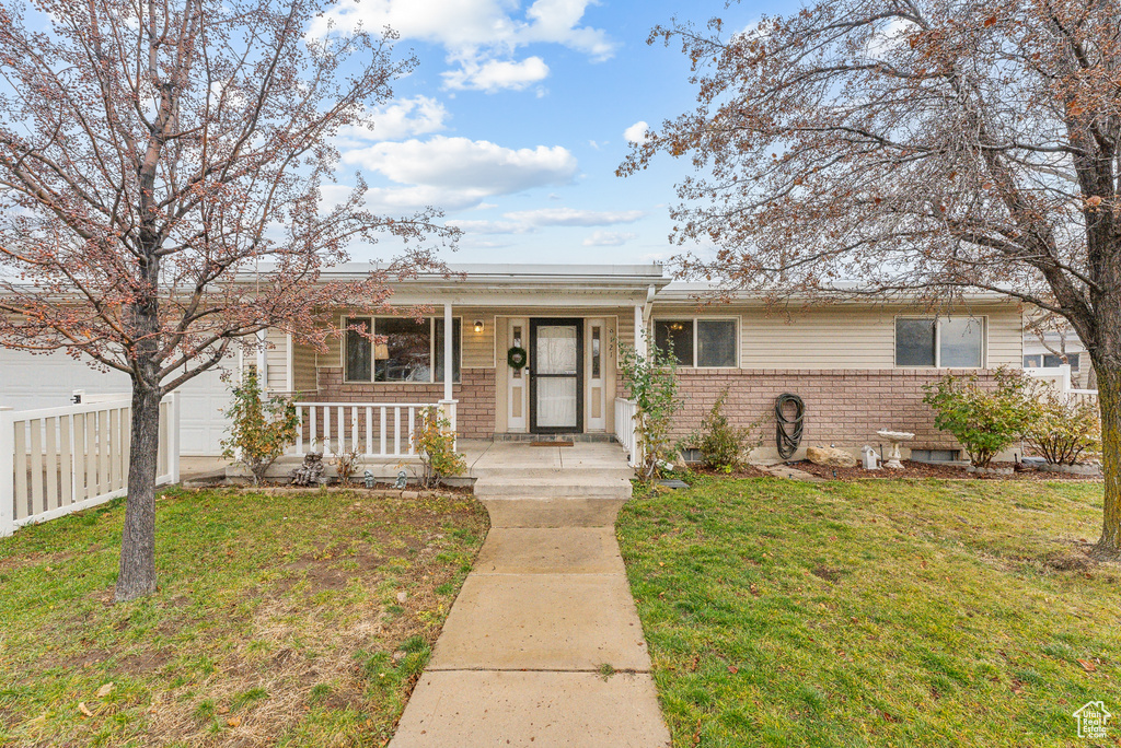 View of front of home with a porch, a garage, and a front lawn