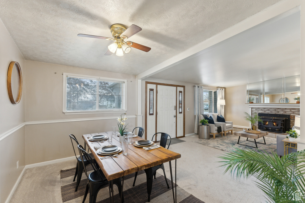 Dining area featuring ceiling fan, light colored carpet, and a textured ceiling