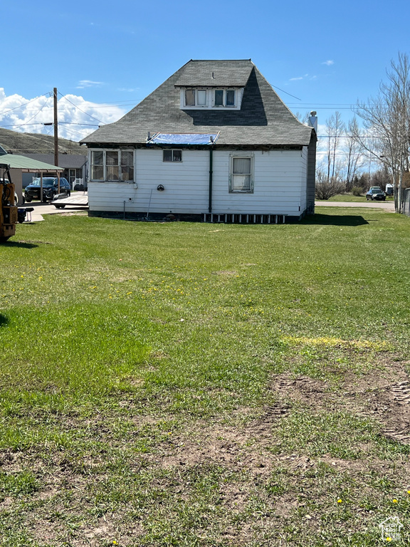 Rear view of property featuring a shingled roof and a yard