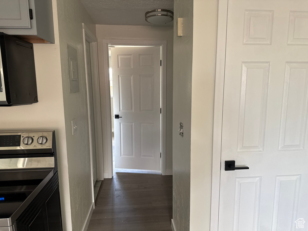 Hall featuring electric panel, dark wood-type flooring, and a textured ceiling