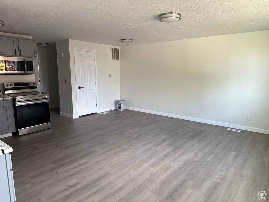 Kitchen featuring gray cabinetry, dark hardwood / wood-style flooring, a textured ceiling, and appliances with stainless steel finishes