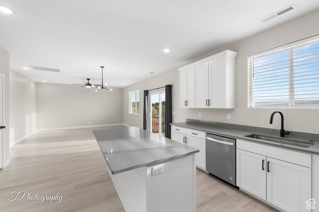 Kitchen with stainless steel dishwasher, sink, light hardwood / wood-style flooring, white cabinets, and a center island