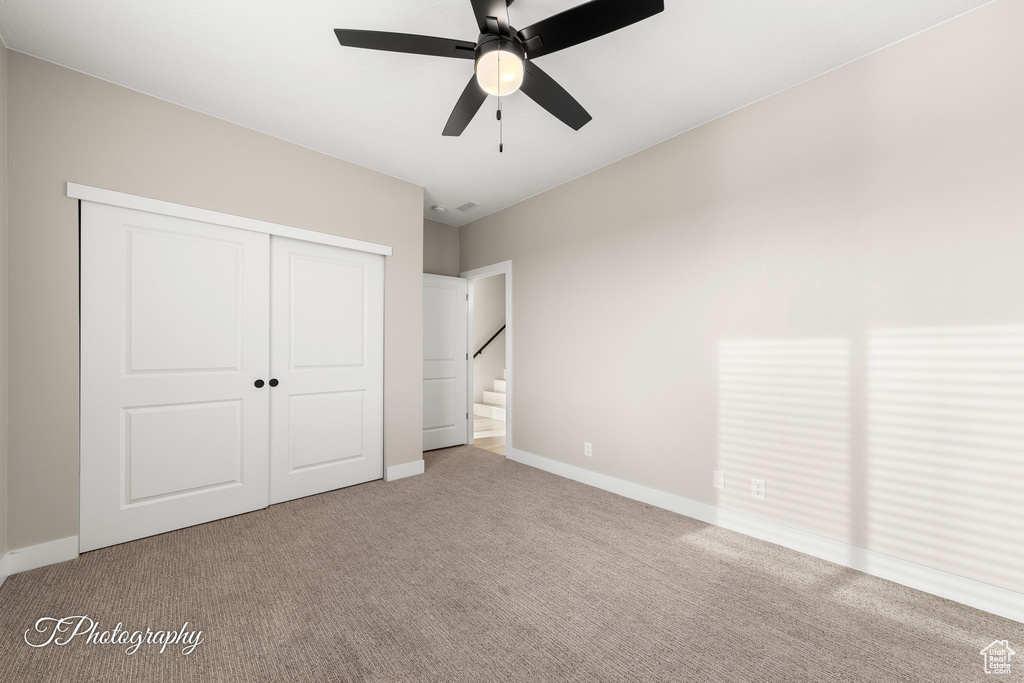 Unfurnished bedroom featuring ceiling fan, a closet, and carpet floors