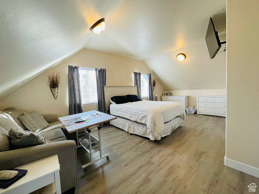 Bedroom featuring light wood-type flooring and lofted ceiling