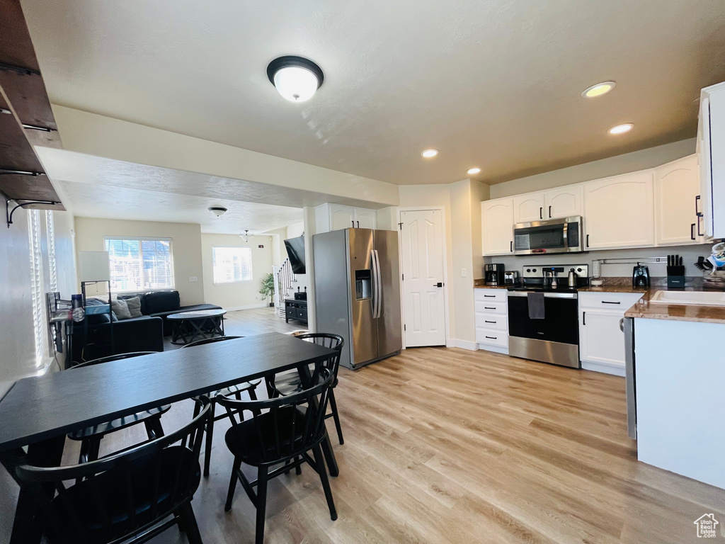 Kitchen featuring white cabinets, sink, appliances with stainless steel finishes, and light hardwood / wood-style flooring