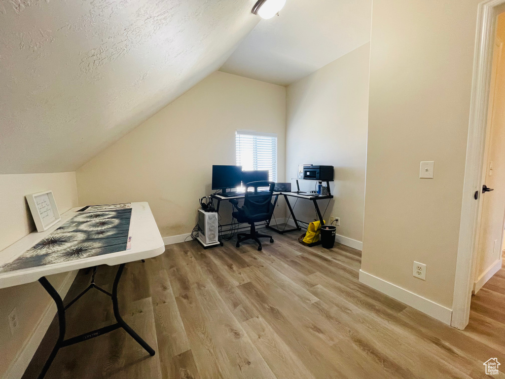 Office with a textured ceiling, light hardwood / wood-style floors, and lofted ceiling