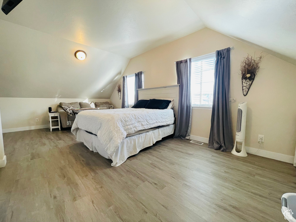 Bedroom with vaulted ceiling and light hardwood / wood-style flooring