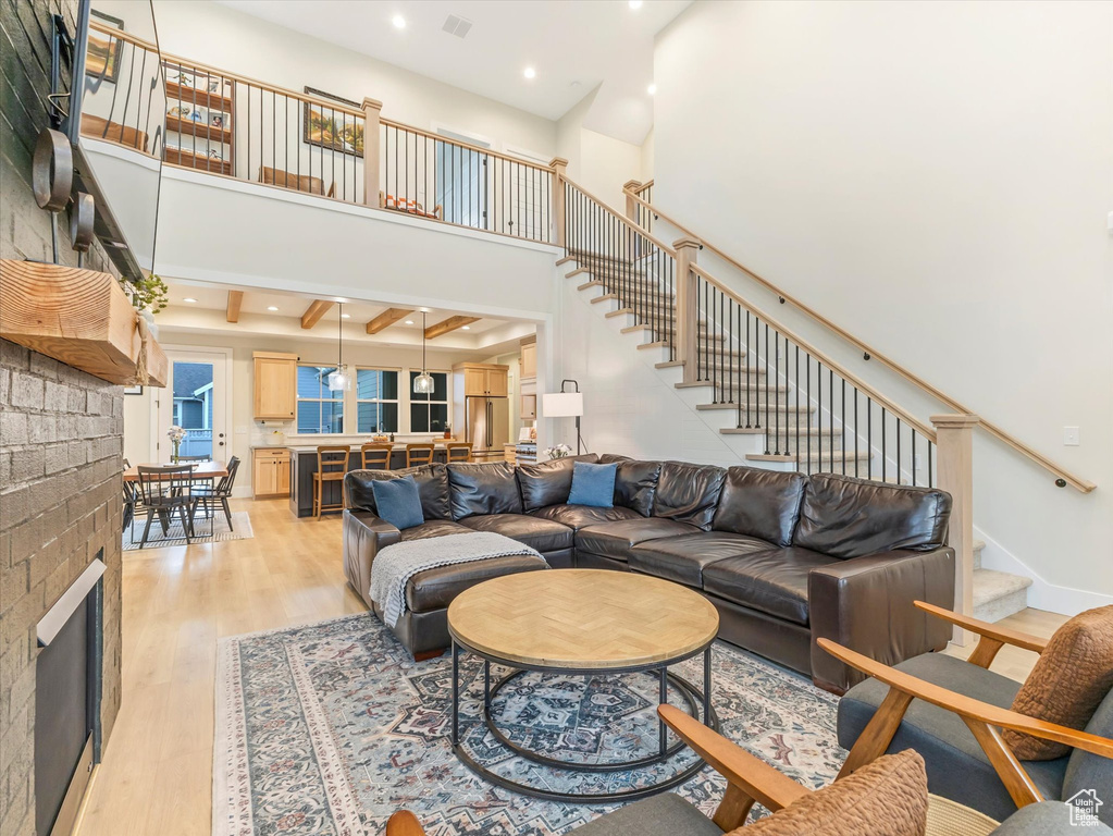 Living room with beamed ceiling, a towering ceiling, and light hardwood / wood-style floors