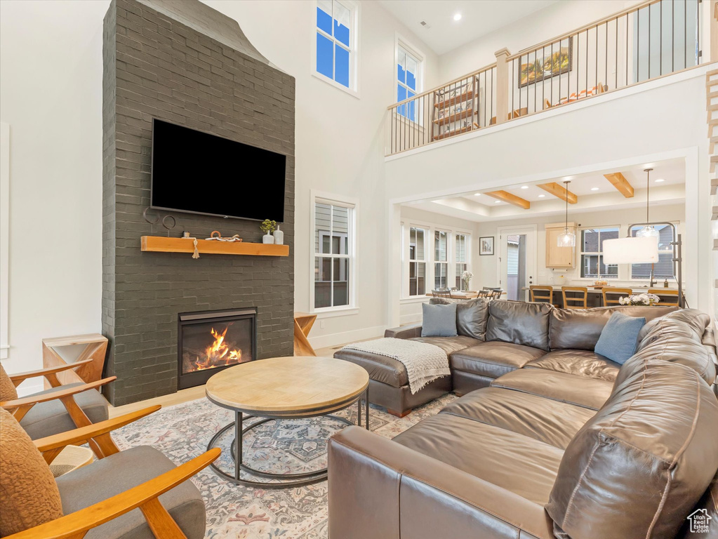 Living room featuring a fireplace, beam ceiling, a towering ceiling, and wood-type flooring