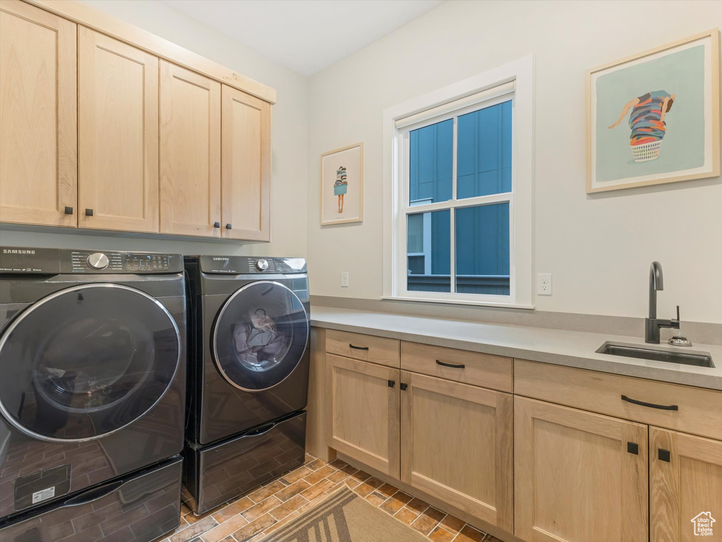 Clothes washing area with cabinets, independent washer and dryer, and sink