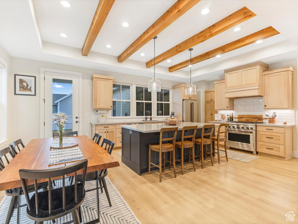 Kitchen with backsplash, high quality appliances, light brown cabinetry, and a center island