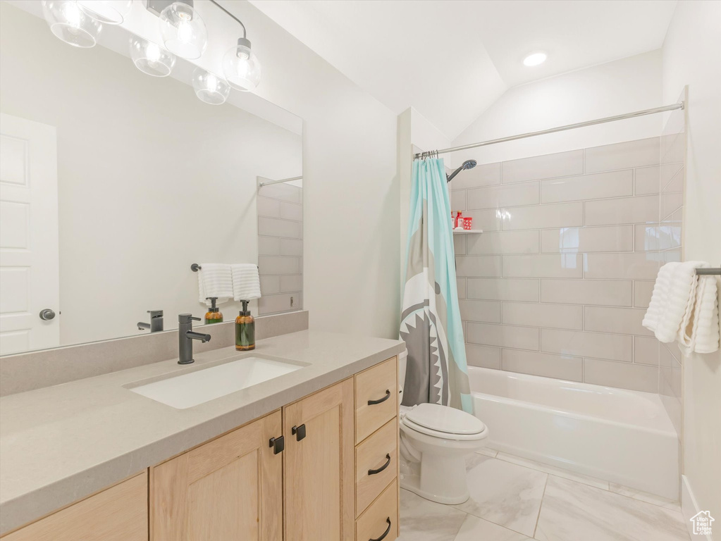 Full bathroom featuring vanity, shower / bath combination with curtain, vaulted ceiling, and toilet