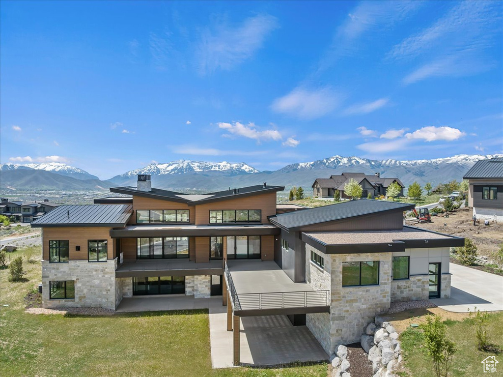 Back of property featuring stone siding, a mountain view, a patio area, and a chimney