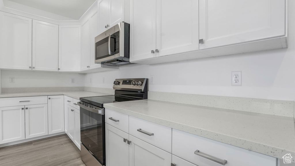 Kitchen featuring stainless steel appliances, white cabinetry, and light wood-type flooring