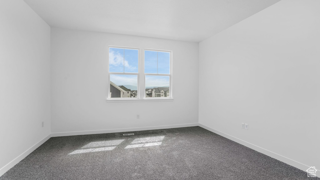 Unfurnished room featuring dark carpet and baseboards