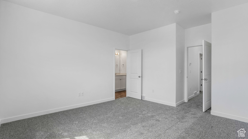Unfurnished bedroom with carpet, baseboards, and ensuite bath