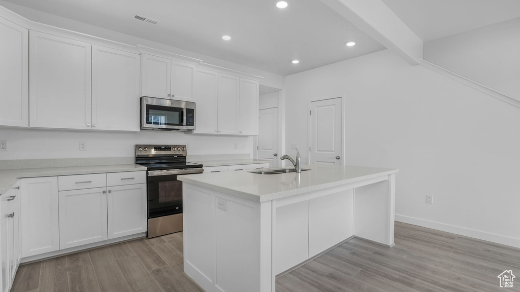 Kitchen featuring stainless steel appliances, a sink, recessed lighting, white cabinets, and light wood-style floors