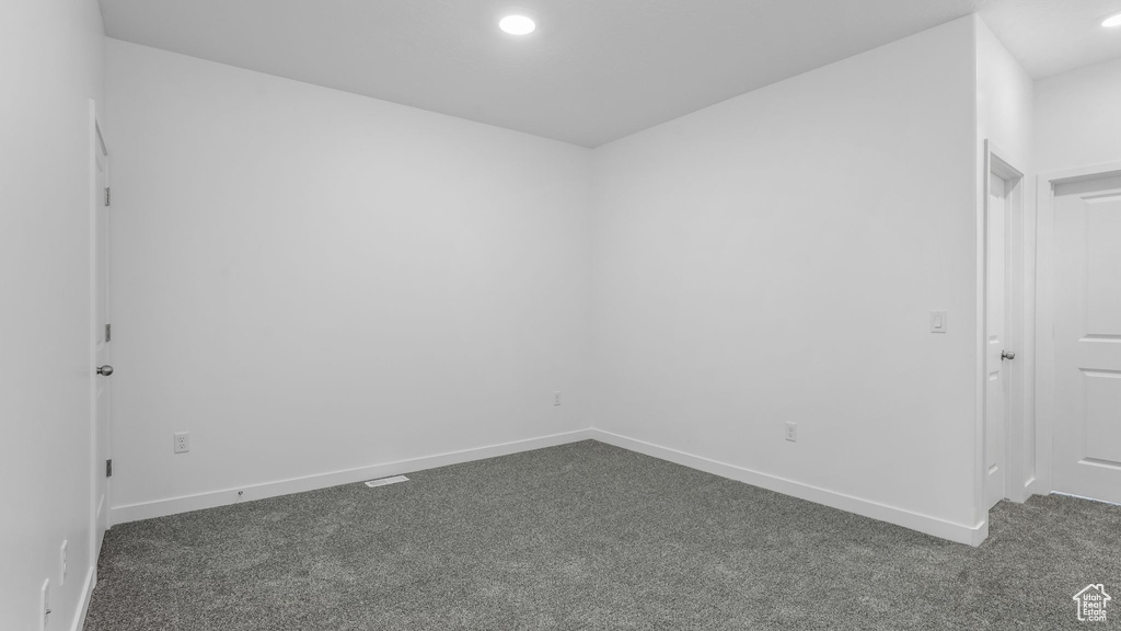 Empty room featuring dark carpet, recessed lighting, and baseboards