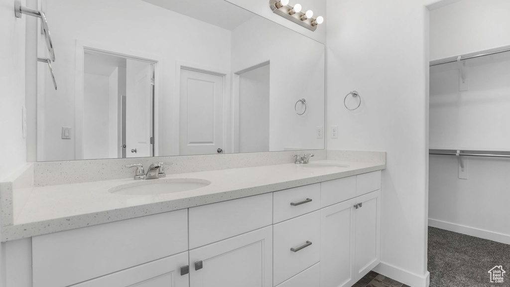 Bathroom with double vanity, a spacious closet, and baseboards