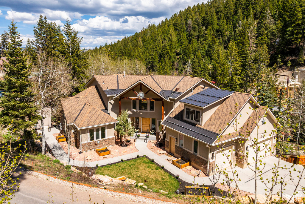 View of front of house featuring stone siding, roof mounted solar panels, stucco siding, and concrete driveway