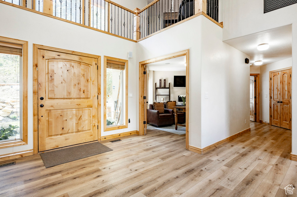 Entryway with wood finished floors, a high ceiling, and baseboards