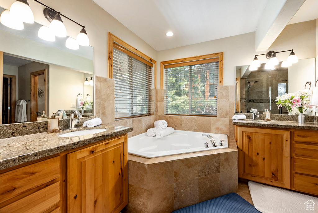 Full bath with a stall shower, a bath, tile patterned flooring, and two vanities